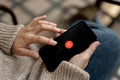 A woman using Youtube music application on her IPhone14 while sitting outdoors. Youtube music logo