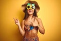 Woman on vacation wearing bikini and pineapple sunglasses over isolated yellow background smiling and looking at the camera Royalty Free Stock Photo