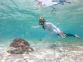 Woman on vacations wearing snokeling mask swimming with sea turtle in turquoise blue water of Gili islands, Indonesia