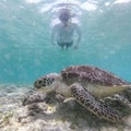 Woman on vacations wearing snokeling mask swimming with sea turtle in turquoise blue water of Gili islands, Indonesia