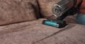 Woman vacuuming dust and dirt on sofa with cordless vacuum cleaner. Technology concept.