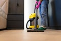 Woman vacuuming the parquet floor in the room with professional vacuum cleaner. Cleaning company employee cleans the house.