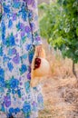 Woman in floral dress with straw hat in hand in grape vineyard