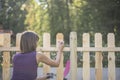 Woman varnishing a wooden picket fence