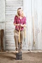 Woman in vegetable garden with the spade isolated on white wooden shed background with gardening tools Royalty Free Stock Photo