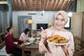 woman in veil carrying a plate of fried chicken with thumbs up in the background family members eating together