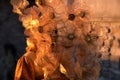 Woman with Venetian mask decorated with gold leaf and orange cloth, stone background