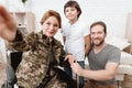 Woman veteran in wheelchair returned from army. The son and husband are happy to see her. Royalty Free Stock Photo