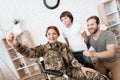Woman veteran in wheelchair returned from army. The son and husband are happy to see her. Royalty Free Stock Photo