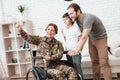 Woman veteran in wheelchair returned from army. The son and husband are happy to see her. Royalty Free Stock Photo