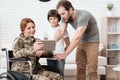 Woman veteran in wheelchair returned from army. The son and husband are happy to see her. Royalty Free Stock Photo