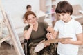 Woman veteran in wheelchair returned from army. Woman in a wheelchair watches her son paints on canvas.