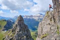 Woman on via ferrata Delle Trincee meaning Way of the trenches, high above impressive pointy rock peak, with Sella group Royalty Free Stock Photo