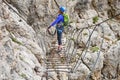 Woman on via ferrata suspended wire bridge at Cesare Piazzetta klettersteig route, Dolomites mountains, Italy. Royalty Free Stock Photo
