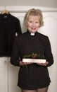 Woman vicar holding a sprig of Holly