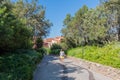 Woman view from behind walks along the path of a quiet Park in Porto Rotondo Sardinia on a clear day