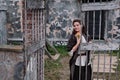 A girl in vintage clothes stands in front of an old building in medieval Europe. Brunette woman with a bouquet of flowers at the Royalty Free Stock Photo