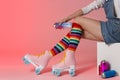 Woman with vintage roller skates and spray paint cans on color background Royalty Free Stock Photo