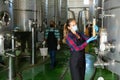 Woman vintner in mask checking wine process