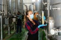 Woman vintner in mask checking wine process