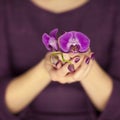 Woman in violett 50`s dress hands holding some orchid flowers Royalty Free Stock Photo
