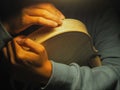violin maker luthier hands roughing the edges of a raw blank violin with sandpaper
