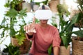 Woman, virtual reality and headset with a finger at home for metaverse, 3d world or future. Female person with plants