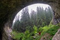 Woman visit geologic formation and open arms standing to the mysterious huge rock cave. Wonderful bridge in Bulgaria on tourist