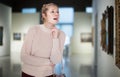 Woman visitor enjoying at exhibition standing near pictures