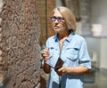 Woman visitor looking at exhibition in museum of ancient sculpture.