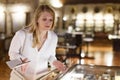 Woman visitor looking to art objects under glass with guide book in museum