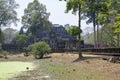 Woman visitor in pink walks the stone causeway supported by many finely carved columns, providing an impressive entrance to the