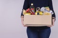 Woman volunteer hands holding food donations box with food grocery products