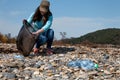 Woman volunteer helps clean the beach of plastic garbage. Earth day and environmental improvement concept. Stone coast on the