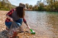 Woman volunteer helps clean the shore of river of garbage. Earth day and environmental improvement concept. Eco. Tint
