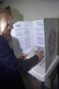 Woman voter in a voting booth selecting choices on a ballot, CA