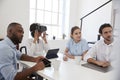 Woman in VR goggles at a desk with colleagues in an office