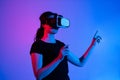 Woman wearing virtual reality headset and interacting with virtual space using both hands in futuristic neon studio environment Royalty Free Stock Photo