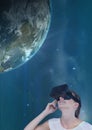 Woman in VR headset looking up to a 3D planet against blue sky Royalty Free Stock Photo