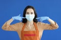 Woman waiter in rubber gloves showing protective mask on her face