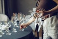 Woman waiter takes few empty wine glasses from bar table, close up without face. Restaurant service and staff serving. Royalty Free Stock Photo