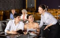 Woman waiter takes order from young couple in restaurant Royalty Free Stock Photo