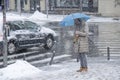 Woman waiting at crossroad under blue umbrella on a snowy city street during heavy snow fall Royalty Free Stock Photo