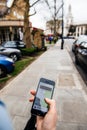 Woman waiting for the uber car on the street holding smartphone Royalty Free Stock Photo