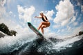 Woman wake surfer jumping up the splashing wave against on blue sky