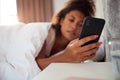 Woman Waking Up In Bed Immediately Reaches Out To Look At Mobile Phone Royalty Free Stock Photo