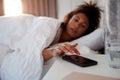 Woman Waking Up In Bed Reaches Out To Turn Off Alarm On Mobile Phone Royalty Free Stock Photo