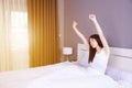 Woman waking up and hand raised on bed in bedroom Royalty Free Stock Photo