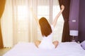 Woman waking up and hand raised on bed in bedroom Royalty Free Stock Photo