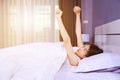 Woman waking up and hand raised on bed in bedroom Royalty Free Stock Photo